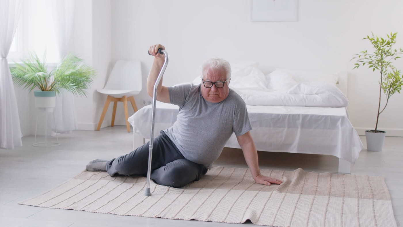 An older man rising from the floor with a cane, the kind of event KiQ recognizes automatically.